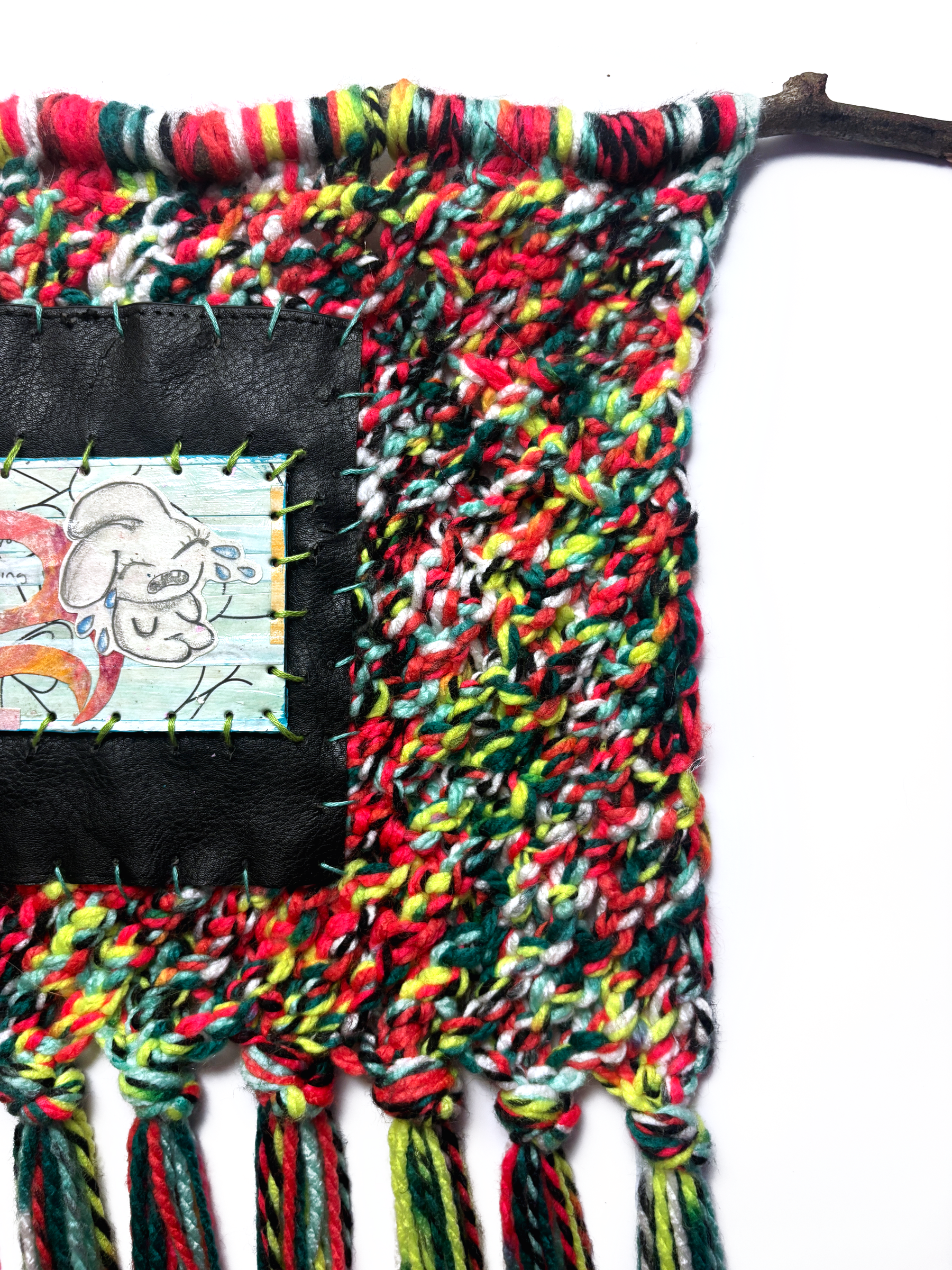 Detail of the top: the branch, the knitted yarn and the edge of the black panel.